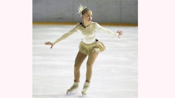 リンクの上で演技中の綺麗な衣装を身に纏ったフィギュアスケート女子選手
